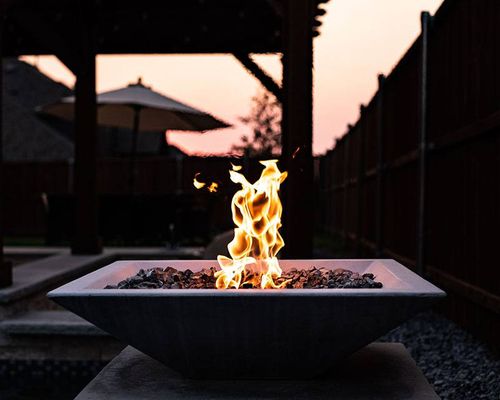 square fire bowl lit up at night on a patio