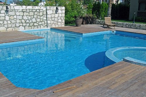 rectangular pool with built-in hot tub and water feature