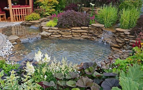 multi-tiered pond with waterfalls between each tier and plants surrounding