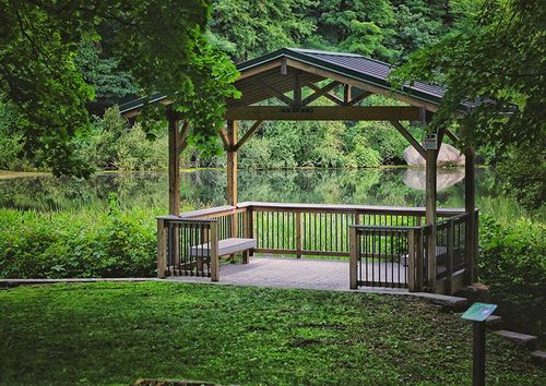 gazebo with bench seating next to a small pond