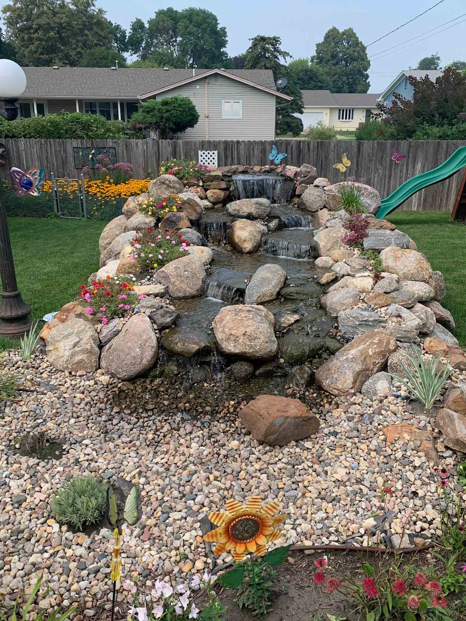 backyard waterfall with boulders and flowers