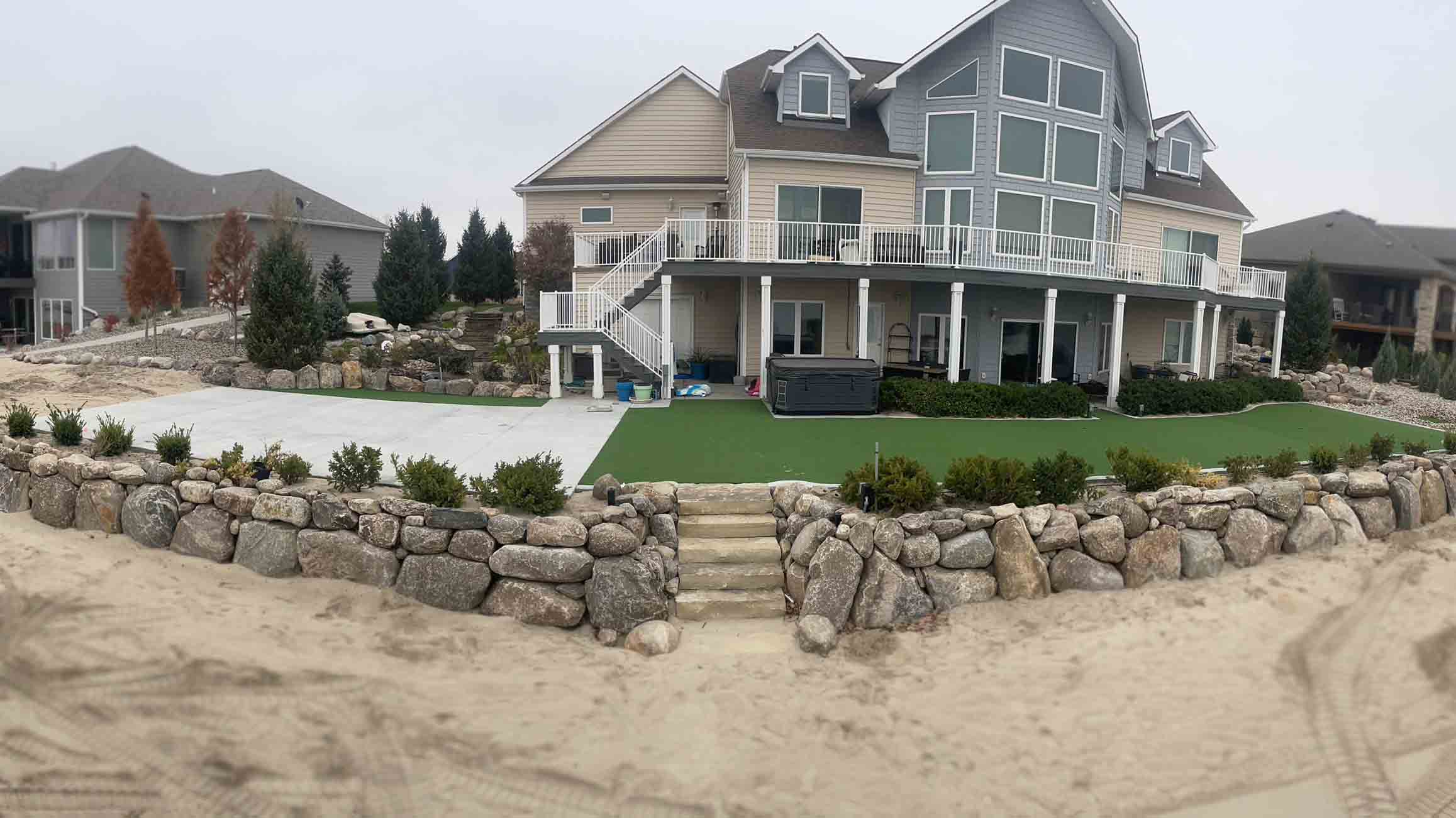 lake house with boulder wall and astroturf